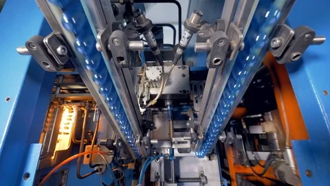 PET bottle preforms grabbed and elevated to enter blowing chamber. Stock Footage 77384445