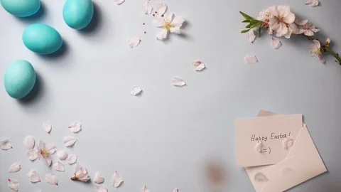 Petals fall on blue background with easter eggs and greeting card Stock-Footage 126285809