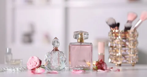 Petals falling onto bottles of perfume and beautiful flowers at white table Stock-Footage 304920430