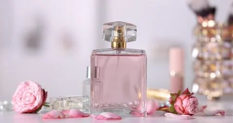 Petals falling onto bottles of perfume and beautiful flowers at white table Stock-Footage 305020702