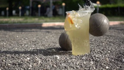 A petanque ball knocks down a cup with a drink. Stock Footage 108687882