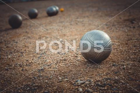 Petanque balls on a sandy pitch with other metal ball in the background ...