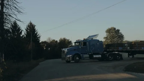 Peterbilt semi truck pulling out of yard and driving down the street front Stock Footage 97900575