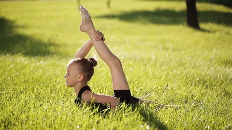 Petite flexible girl does in the grass complex gymnastic exercises. Stock Footage 64771982