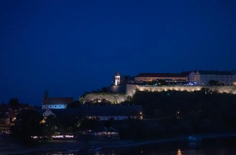 Petrovaradin fortress complex with clock tower illuminated on hill at night Stock Photos