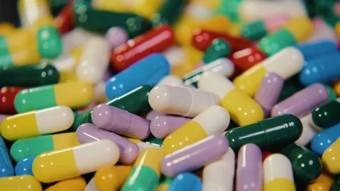 Pharmaceutical drug, a bunch of multi-colored round capsules of tablets with Stock Footage 102027876