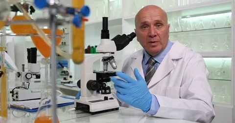 Pharmaceutical Lab Chemist Use Microscope and Give Interview Talk and Explain Stock Footage 83687372