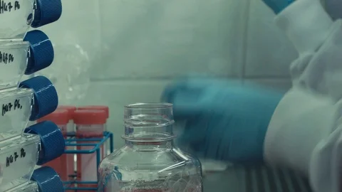 Pharmaceutical lab removing cap of bottle and transferring red liquid to Stock Footage 99068696