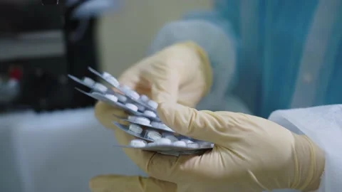A pharmaceutical production worker checks the packaging of medicines on the Stock Footage 199685870
