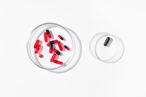 Pharmaceutical research and development with red and black pills in petri dis Stock Photos