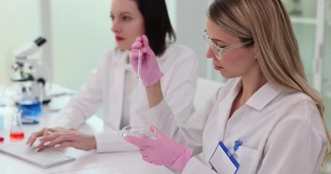 Pharmaceutical researcher analyzes test solution from petri dish to advance Stock Footage 265945914
