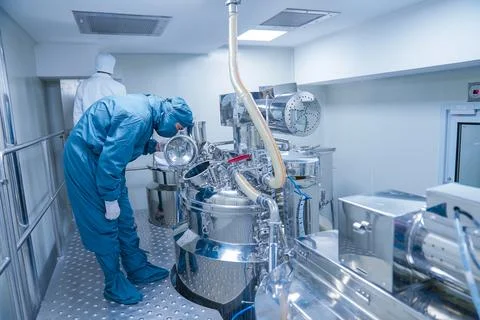 Pharmaceutical worker using large machine. person checking medicine liquid makin 写真素材