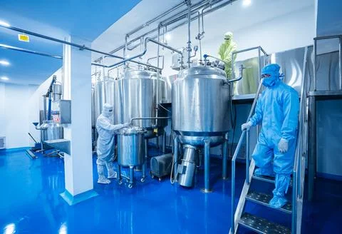 Pharmaceutical worker using large machine. person checking medicine liquid makin Stock Photos