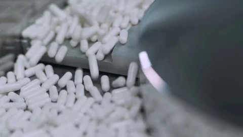 Pharmaceuticals, large number of capsules, white tablets on the conveyor. Stock Footage