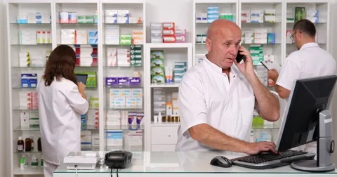 Pharmaceutist Talking to Mobile with a Client Employee Working in Pharmacy Stock Footage 83673820