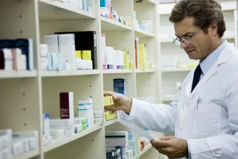Pharmacist checking shelf for medication Stock Photos