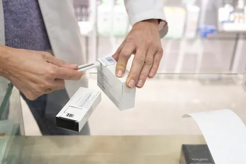 A pharmacist cuts out the barcode on a medication to control inventory and Stock-Fotos