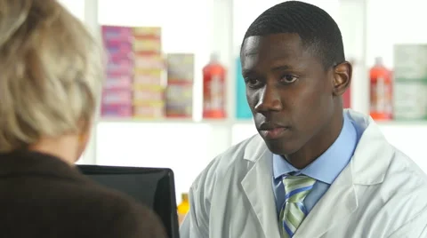 Pharmacist entering customer information into computer at pharmacy Stock Footage 58222966