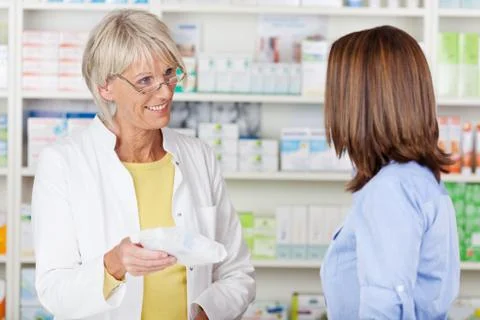 Pharmacist giving prescribed medicine to customer in pharmacy Stock Photos