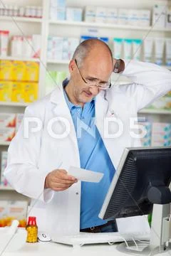 Pharmacist holding prescription paper at counter Stock Photos