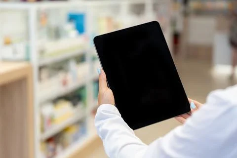 Pharmacist looking at the black screen of a digital tablet in the pharmacy Stock Photos