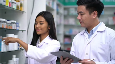 Pharmacist man holding computer tablet and Pharmacist woman Inspecting medicine 動画素材 136939555