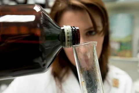 Pharmacist pours a solution. Clip about medicine, chemistry and science. Stock Photos