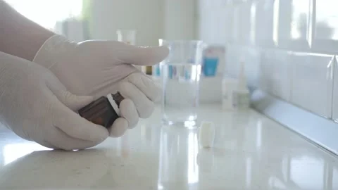 Pharmacist with Protective Gloves in Hands Putts Some Medical Pills in Recipient Vídeo Stock 153589295