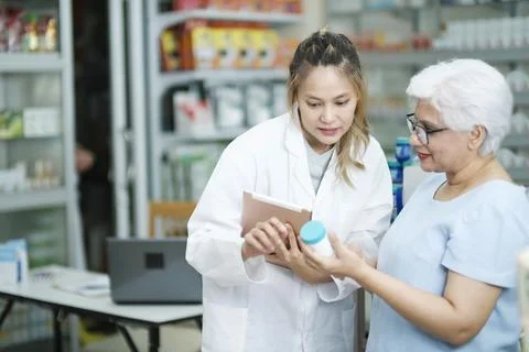 Pharmacist talking to a client about prescribed medications. Stock Photos