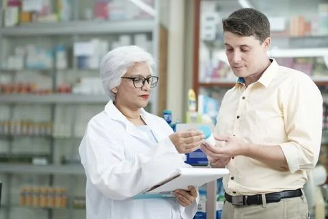 Pharmacist talking to a client about prescribed medications. Stock Photos