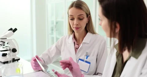 Pharmacist tests knowledge of assistant with test on tablet Stock Footage 265085861