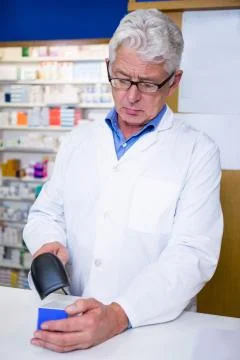 Pharmacist using barcode scanner on medicine box in pharmacy Stock-Fotos