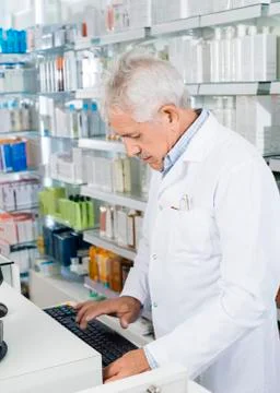 Pharmacist Using Computer Keyboard At Counter 写真素材