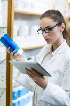 Pharmacist using digital tablet while checking medicine in pharmacy Stock Photos
