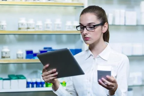 Pharmacist using digital tablet while checking medicine in pharmacy 写真素材