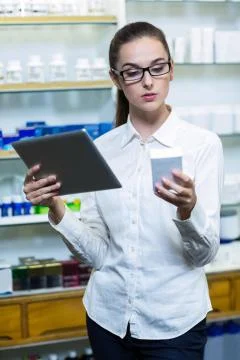Pharmacist using digital tablet while checking medicine in pharmacy Fotos de archivo