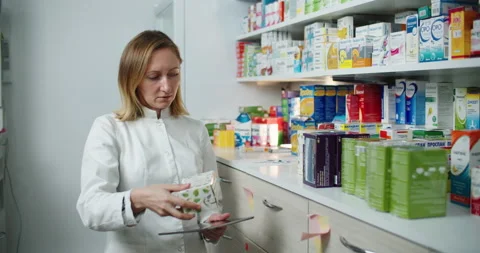 Pharmacist woman checks medicines at the pharmacy and writes the data on the Stock Footage