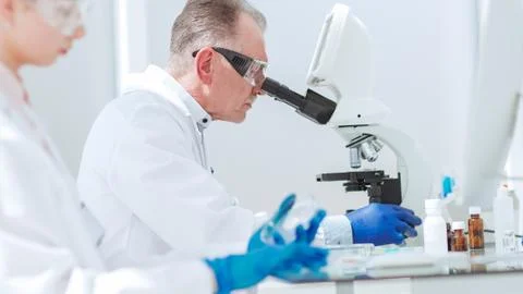 Pharmacists from all over using microscope in the laboratory. Stock Photos