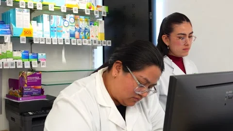 Pharmacists working together on a computer at the drugstore Stock Footage 336358864
