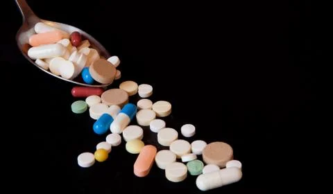 Pharmacy background on a black table. Tablets with a spoon. Pills. Medicine a Stock Photos