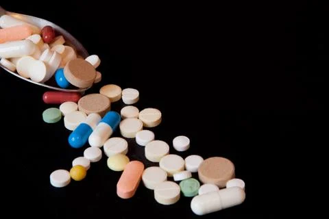 Pharmacy background on a black table. Tablets with a spoon. Pills. Medicine a Stock Photos