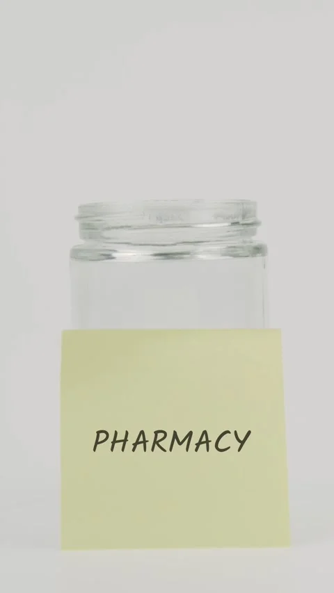 Pharmacy text or word on yellow sticky note attached to glass jar with hand Stock Footage 311766588