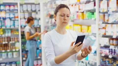 In pharmacy visitor scan QR Code and reads composition of cream for problematic Video stock 248939893