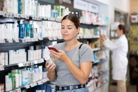 In pharmacy visitor scan QR Code and reads composition of cream for problematic Stockfoto's