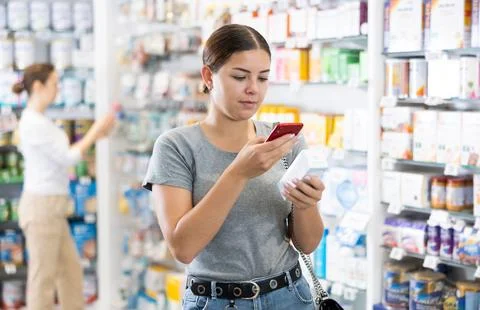In pharmacy visitor scan QR Code and reads composition of cream for problematic 스톡 사진