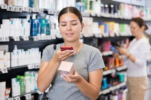 In pharmacy visitor scan QR Code and reads composition of cream for problematic Stock Photos