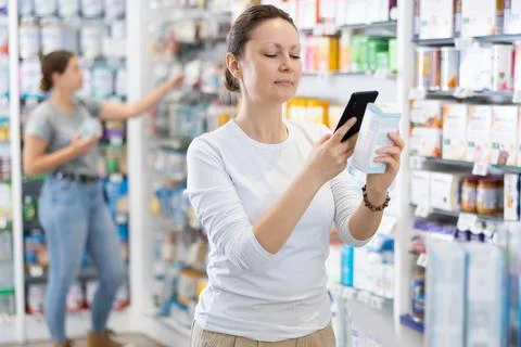 In pharmacy visitor scan QR Code and reads composition of cream for problematic Stock Photos