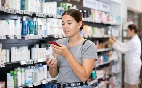 In pharmacy visitor scan QR Code and reads composition of cream for problematic Foto stock