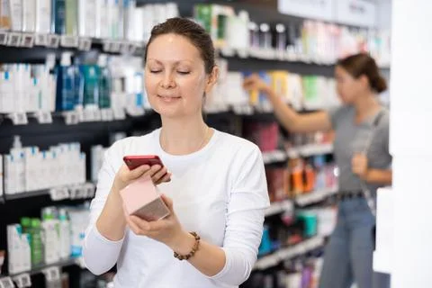 In pharmacy visitor scan QR Code and reads composition of cream for problematic Foto stock