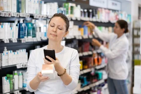 In pharmacy visitor scan QR Code and reads composition of cream for problematic Stock-Fotos